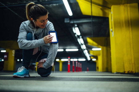 在地下停车场使用手机的女运动员肖像