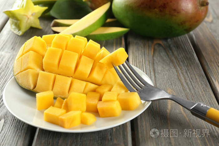 餐桌上有鲜切芒果的叉子和盘子特写