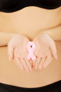 女人抱着粉红色乳腺癌癌症丝带