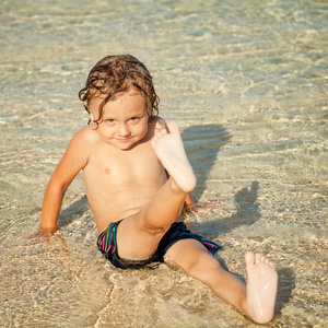 小男孩坐在沙滩上，在白天的时间