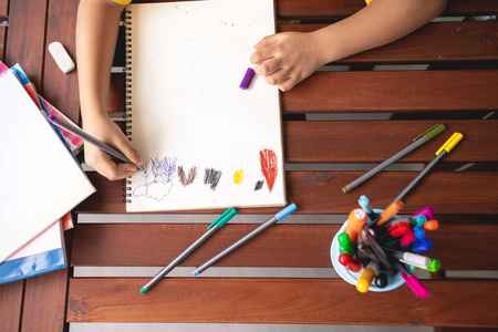 儿童作业。年轻的混血男孩在家的露台做作业。绘制着色。集中心情。回到学校的概念。美景