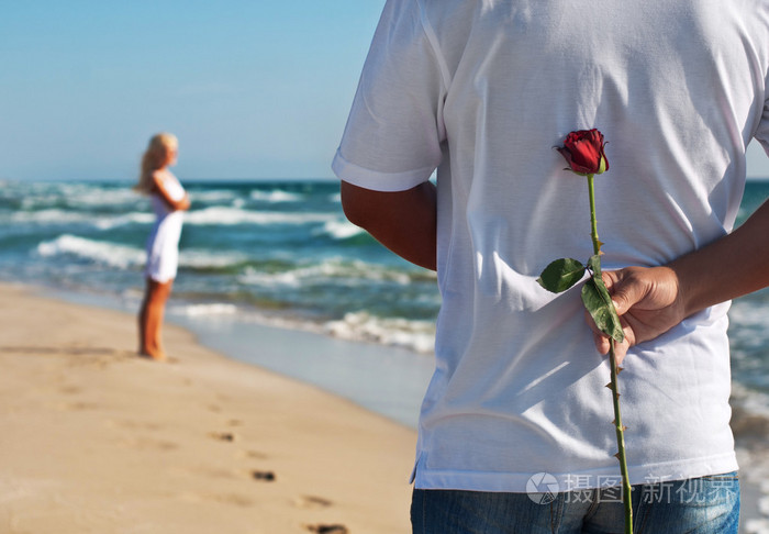 恩爱的夫妻,玫瑰等海沙滩上他的女人的男人