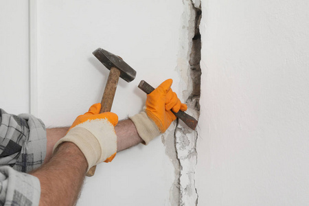 用凿刀锤施工工人在砖墙上拆除洞