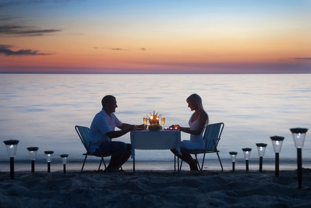 一对年轻夫妇与蜡烛和葡萄酒 gla 共享浪漫的晚餐