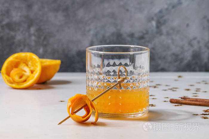 杯苏格兰威士忌橙汁酒精鸡尾酒与盘旋橙色果皮在串和肉桂棍子站立在