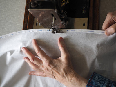 缝纫过程。脚旧老式缝纫机和老妇人的手。选择性聚焦