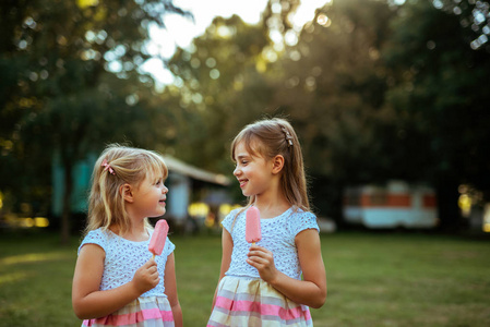 两个年轻漂亮的女孩在公园里吃冰激淋的肖像