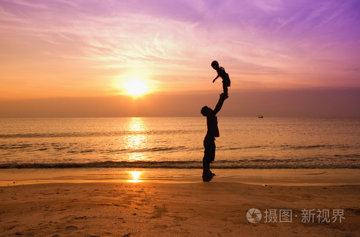父亲和儿子在日落海滩上的剪影