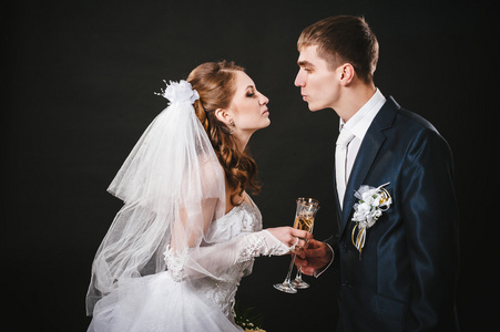婚礼情侣接吻和喝香槟。黑色背景