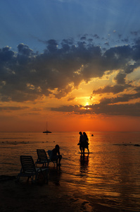 在日落期间在海上行走的人的剪影