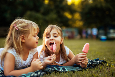 两个金发妹妹在公园里野餐吃冰激淋