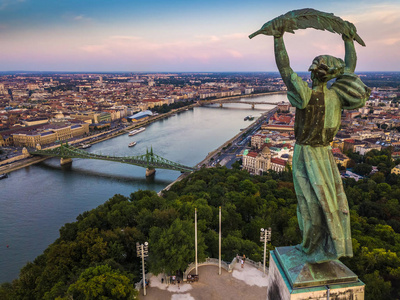 匈牙利布达佩斯在日落时自由女神像的鸟瞰图, 背景为布达佩斯图书馆桥和多瑙河的地平线