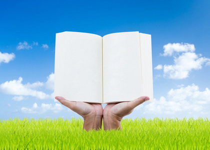 男人手里拿着本书在绿色的田野 蓝蓝的天空背景上