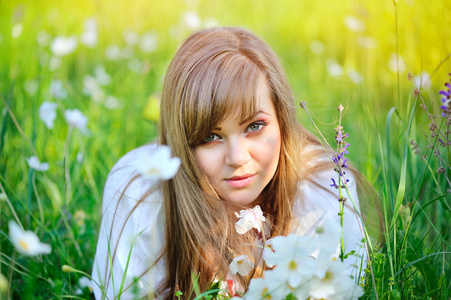美丽的年轻女子在草地上用白色花上一天的温暖的夏天
