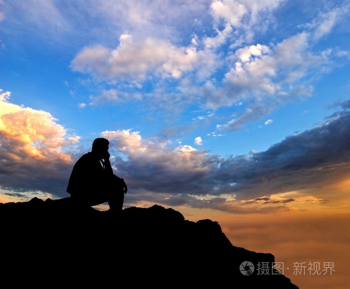 坐在一个晚上的天空背景上的男人剪影