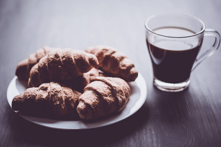 美国咖啡和新鲜的牛角面包在黑色的背景。早餐的概念。甜点和咖啡。伙计穆迪的颜色。特写