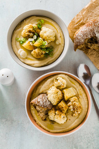 奶油汤的花椰菜和土豆碗在桌子上, 新鲜的面包和葱。健康素食食谱