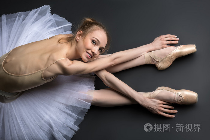 优雅的芭蕾舞演员坐在地板上