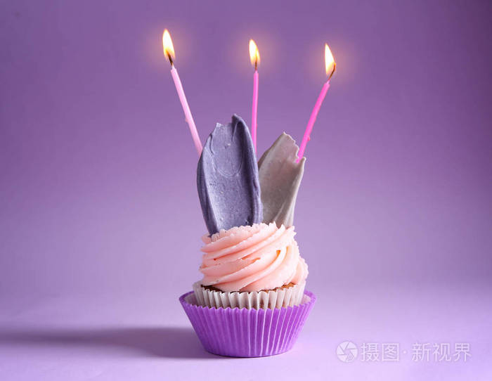 美味的生日蛋糕与燃烧蜡烛的颜色背景