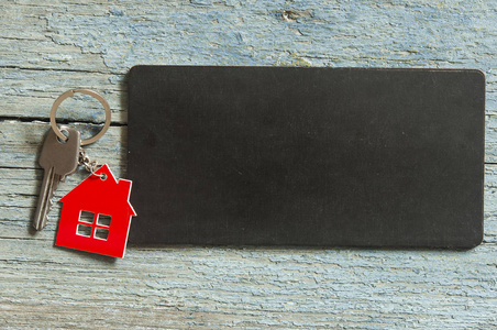 顶部视图符号的房子与银色的钥匙黑色板上的木质背景为您的文本广告或产品