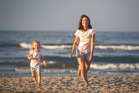海滩上的女人和孩子母亲带着女儿跑向父亲。微笑的女孩在度假。威尼斯, 意大利