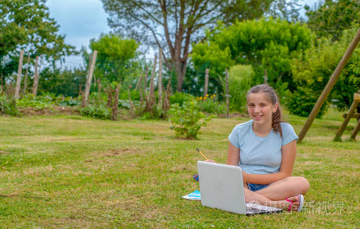 一个年轻的少年坐在草地上使用笔记本电脑照片-正版商用图片0b8kh8-摄