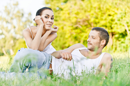 美丽的年轻夫妇坐在草地上