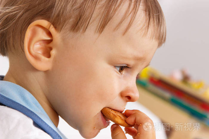 饥饿的小男孩吃饼干或饼干, 儿童的甜点概念在学前或托儿所