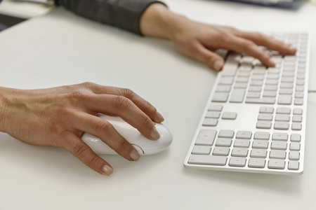 女性手上的计算机键盘和鼠标