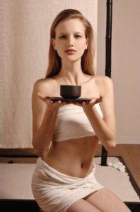 美丽的年轻女子在禅式水疗中心享受一杯凉茶