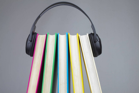 书籍和耳机作为有声读物的概念。在灰色背景下隔离