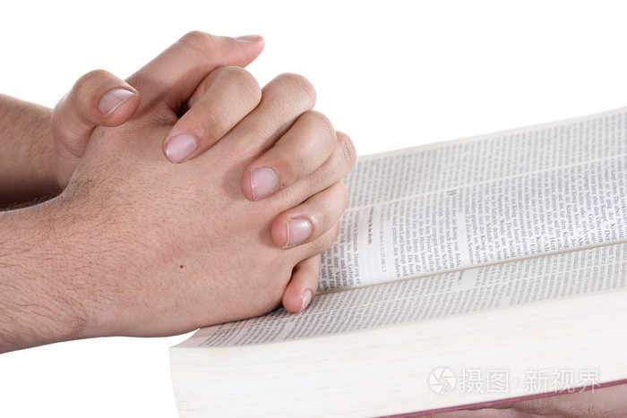 祈祷的手按住打开的圣经