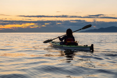 女孩海上皮划艇在一个充满活力的阳光明媚的夏日日落。在加拿大不列颠哥伦比亚省温哥华拍摄