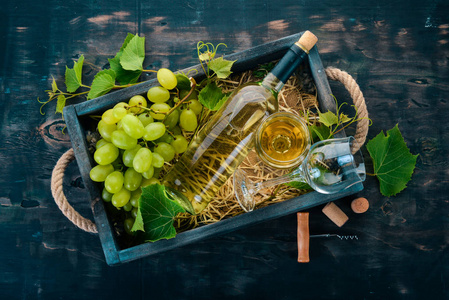 一瓶带眼镜和葡萄的白葡萄酒。叶子的葡萄。顶部视图。在黑色的木质背景。文本的可用空间