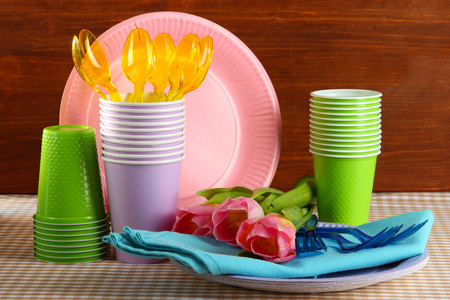 多彩多姿的塑料餐具桌上与木制背景上的郁金香