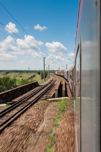 铁路去视界在绿色和黄色的风景，在蓝蓝的天空下与白 clouds.railway 下农村地区多云 sky.scenic 铁路在夏天