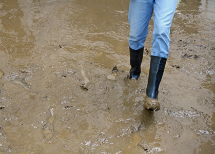 自然灾难后洪水的泥中的黑色靴子照片