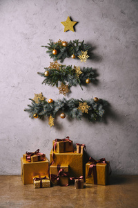 手工圣诞树由树枝挂在灰色墙上, 礼品盒在地板上的房间