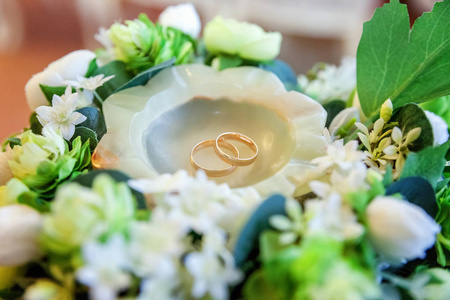 美丽的结婚戒指躺在一张桌子上一束花的背景
