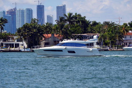 一个小型豪华机动游艇巡航由独家迈阿密海滩岛家园与迈阿密高层建筑在遥远的背景