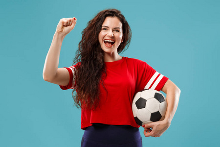 球迷体育女子球员持有足球孤立在蓝色演播室背景。人脸情绪的概念。时尚色彩