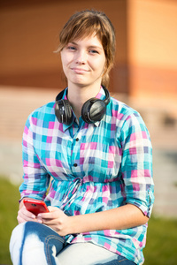 微笑着年轻的大学女孩发短信在手机上。校园