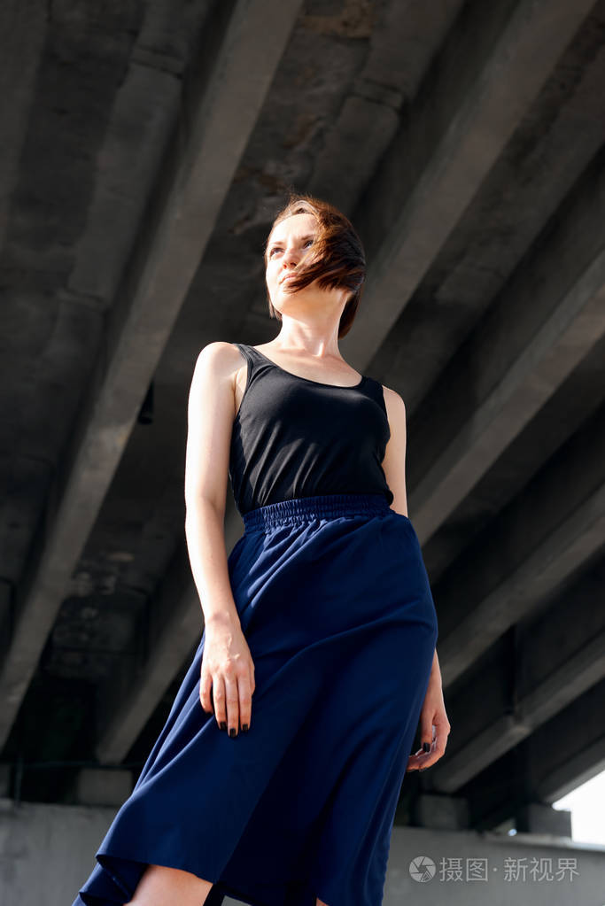 在桥下摆造型的年轻女孩身着黑色现代建筑