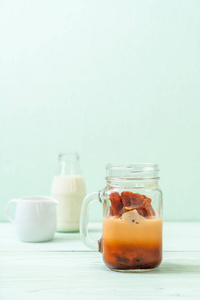 泰国茶冰立方与牛奶在木材背景