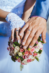 新娘和新郎与婚礼花束上的戒指的手