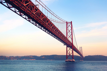 在日落时 25 de Abril 桥和克里斯托怜雕像，葡萄牙里斯本的红色桥