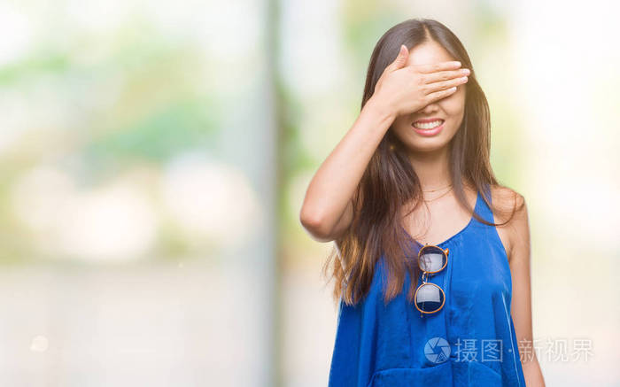 在孤独的背景下年轻的亚洲妇女笑着笑着脸上捂着眼睛惊奇地看着盲目的