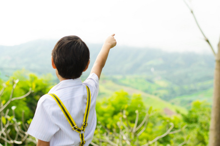 小男孩手指他的手指指向天空在山坡上的小男孩照片