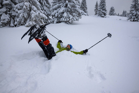 穿雪鞋的快乐冒险家躺在雪地里, 在白雪覆盖的巨大松树中玩耍。冬季史诗般的登山旅行