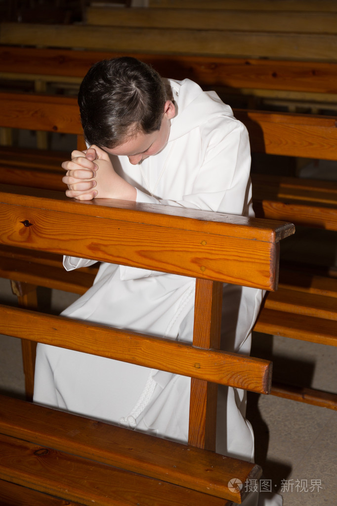 男孩跪在教堂祈祷